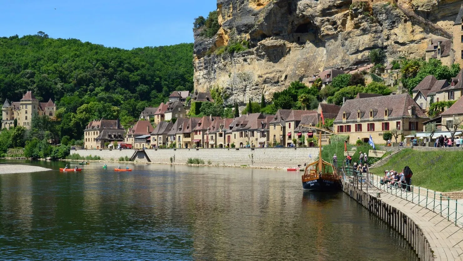 Village en pierre au bord de la Dordogne, falaises en arrière-plan